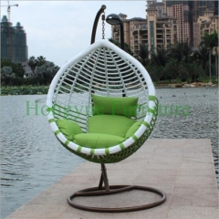 White rattan hammock with green cushions